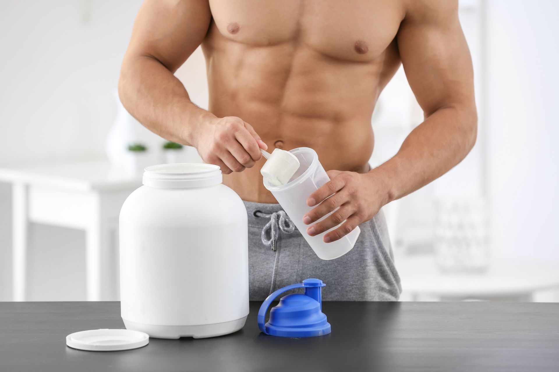 Wysportowany mężczyzna robi shake z odżywką białkową